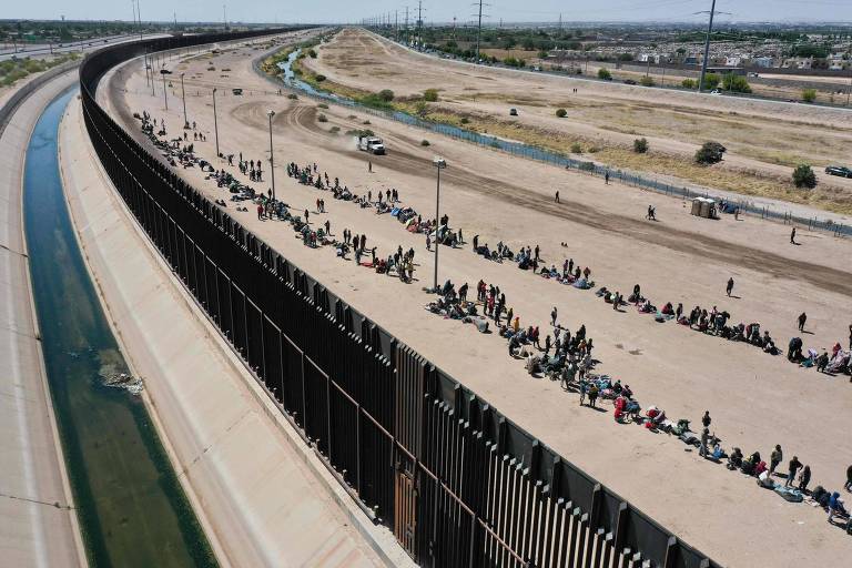 Imagem aérea mostra imigrantes esperando ao lado de muro na região de El Paso, no Texas, na fronteira com o México