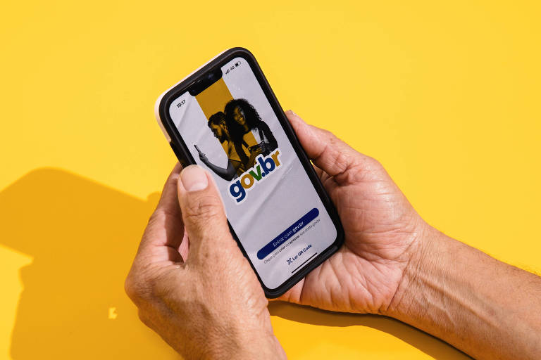 Duas mãos seguram um smartphone contra um fundo amarelo vibrante, exibindo uma tela de aplicativo de transporte com um botão de confirmação,