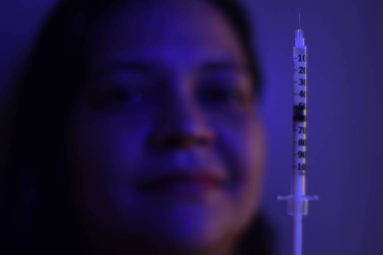 Mulher posa para foto mostrando uma seringa de insulina
