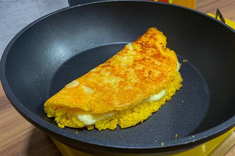 Frigideira com uma tapioca amarela dobrada com recheio de queijo