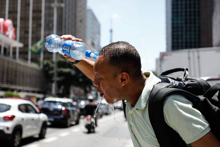 Homem joga água sobre o rosto em novo dia de calor recorde na cidade de São Paulo

