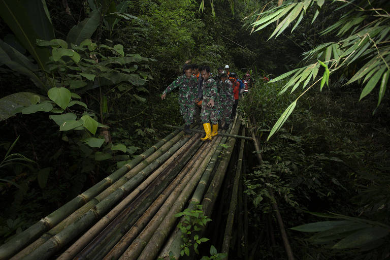 Equipes de resgate carregam alpinista ferido após erupção do Marapi, na Indonésia, para descer o vulcão 