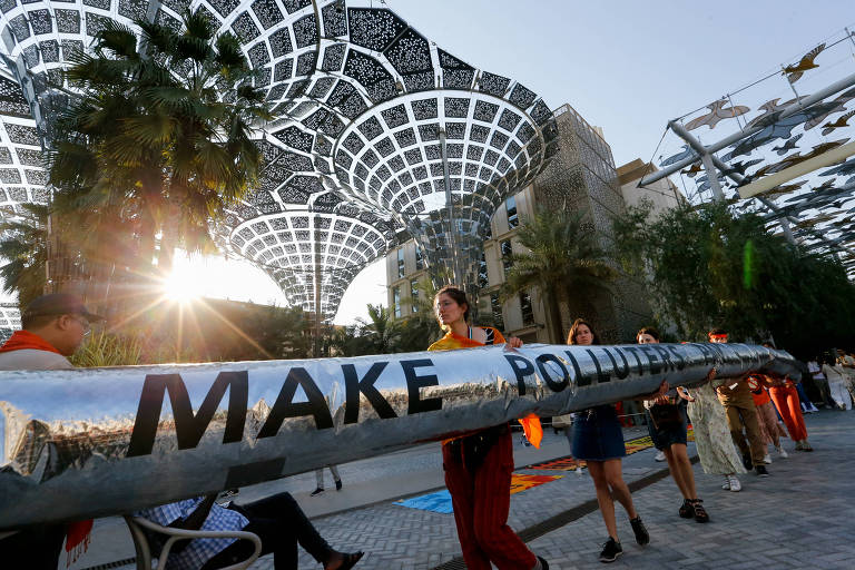 Pessoas carregam faixa com a mensagem em inglês 'make polluters pay'