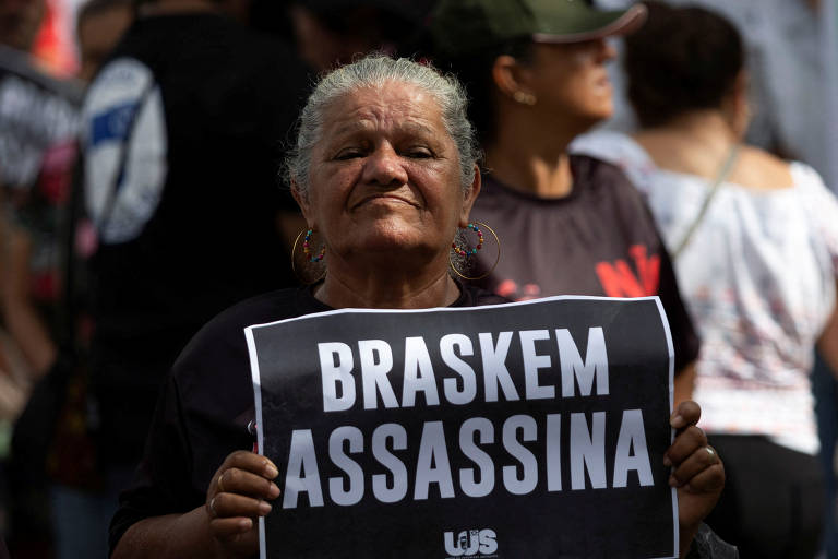 Mulher idosa segura um cartaz escrito braskem assassina