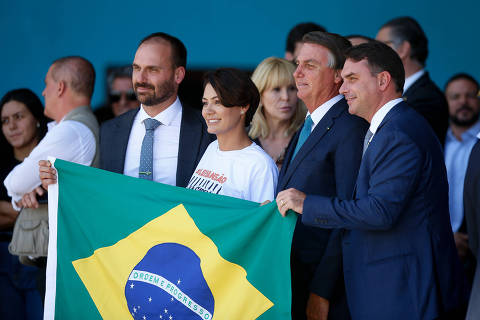 BRASILIA, DF,  BRASIL,  10-03-2022, 12h00: O presidente Jair Bolsonaro e a primeira dama Michelle Bolsonaro , na foto na companhia dos filhos do presidente, Eduardo Bolsonaro (E) e Flávio Bolsonaro (D), recepcionam os brasileiros refugiados da guerra na Ucrânia, que foram resgatados em uma operação da força aérea. Pessoas de outras nacionalidades e animais domésticos também vieram no avião cargueiro KC-390, da FAB. Na base aerea de Brasília. (Foto: Pedro Ladeira/Folhapress, PODER)