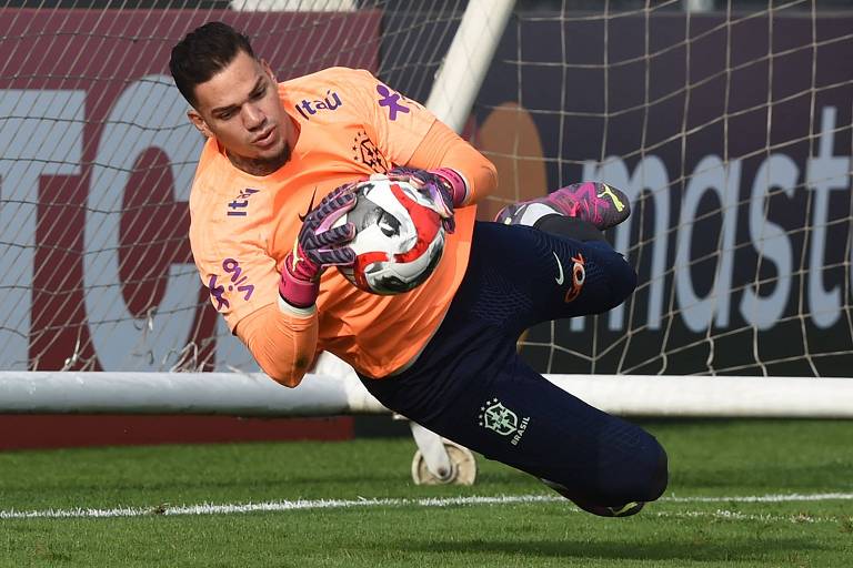 Usando uma camisa laranja, o goleiro Ederson defende uma bola em treino da seleção brasileira em Lima, no Peru, antes de partida das Eliminatórias da Copa do Mundo de 2026