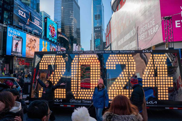 Transeuntes posam após cerimônia de iluminação na Times Square em 20 de dezembro de 2023, na cidade de Nova York.