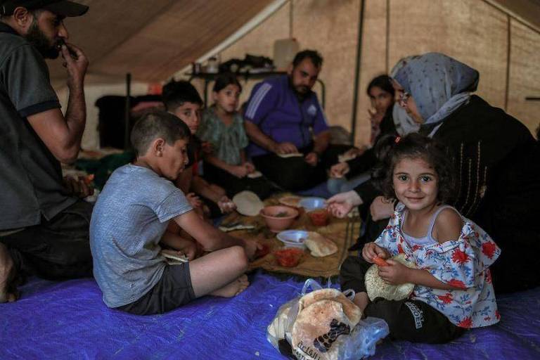 Família de refugiados comendo dentro de tenda