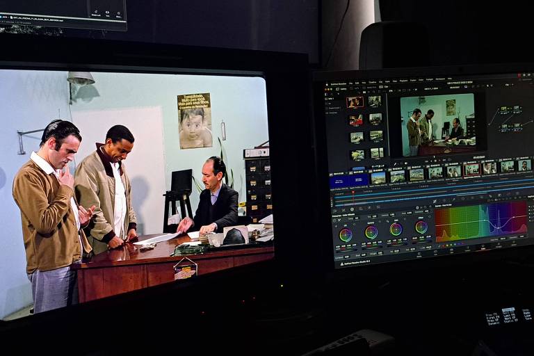 a foto registra uma etapa do processo de digitalização. nela, imagens do filme aparecem lado a lado, em dois monitores de computador, junto a outros marcadores técnicos