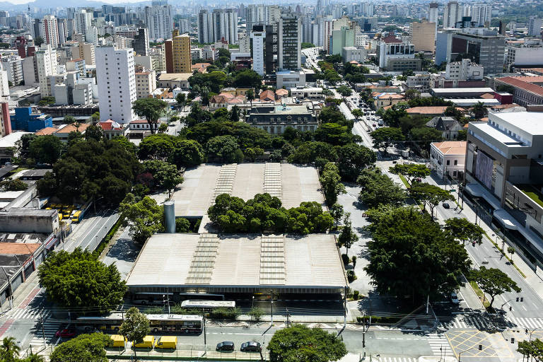 Imagem aérea mostra um grande telhado, sob o qual fica o terminal de ônibus, e árvores de um parque ao fundo