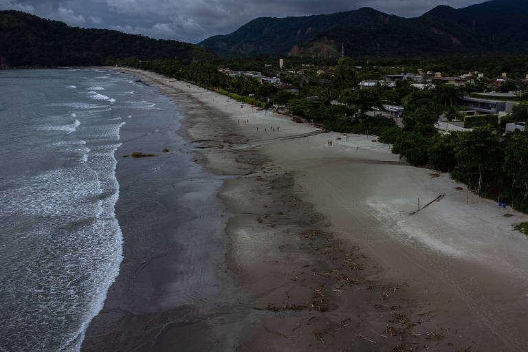 Vista aérea de praia em dia nublado, com imagem dividida entre mar e areia