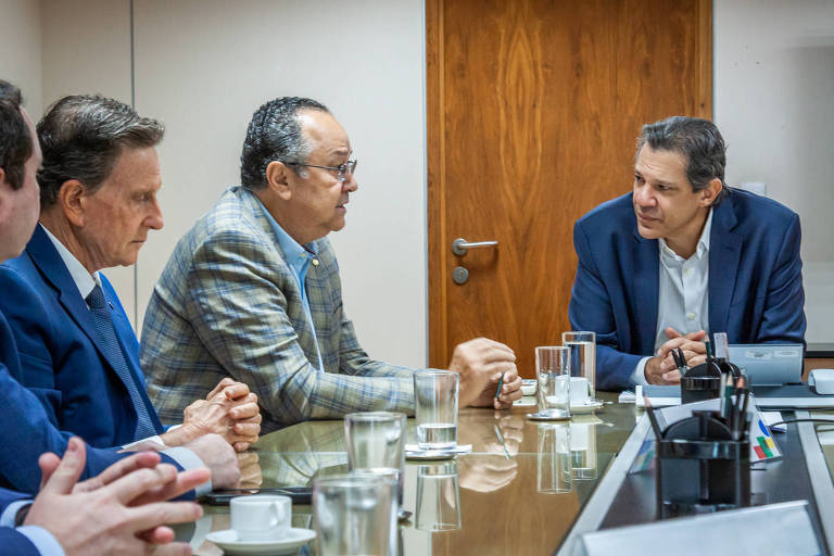 Sala de reunião com o ministro e parlamentares sentados em torno de uma mesa