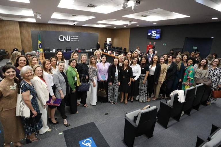 Um grupo de várias mulheres posicionadas lado a lado entre cadeiras e o plenário do CNJ