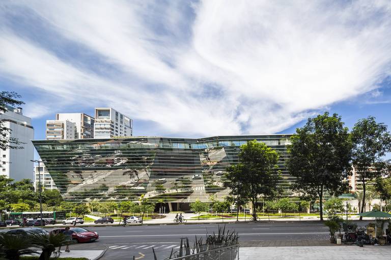 Foto de prédio espelhado e moderno, de baixa estatura, em rua arborizada