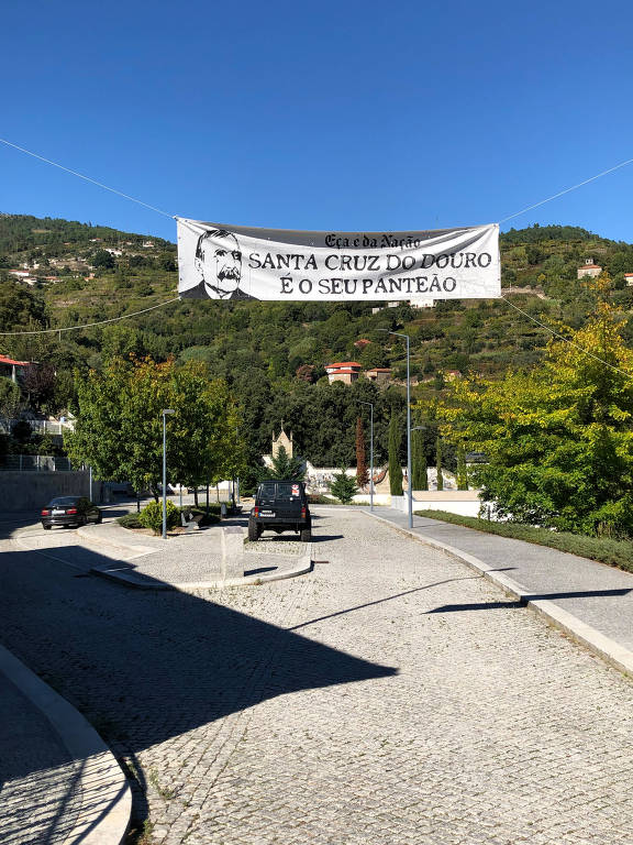 faixa branca com dizeres pretos erguidos sobre estrada de pedra em dia de sol