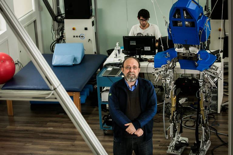 O pesquisador na área da neurociência, Miguel Nicolelis,  ao lado de exoesqueleto, demonstrado com pacientes, antes em cadeiras de rodas