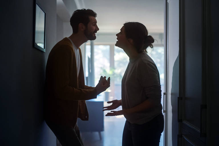 Silhueta de um casal discutindo no corredor de uma casa