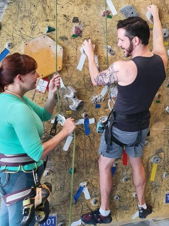 Os escaladores Thais Cavicchioli e Thomas Cavicchioli Dias, em parede da academia Casa de Pedra, usam sapatilhas, cadeirinha e saco de magnésia 