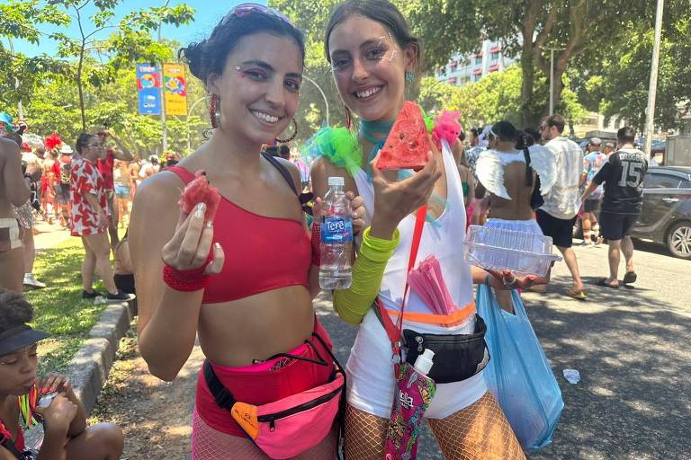 As irmãs Maria Theresa (esq.) e Camila (dir.) compraram melancia para aguentar o calor no bloco Boi Tolo, no Rio 