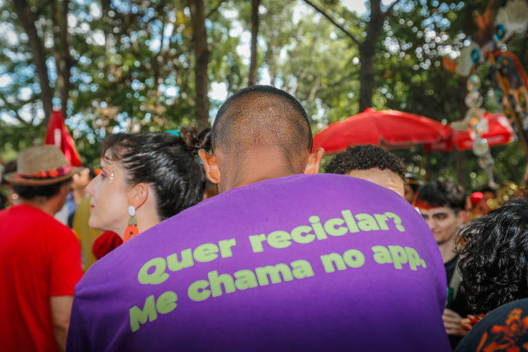 Lucas Assumpção com o uniforme da organização que apoia a contratação de catadores por blocos para gestão dos resíduos do carnaval. Na foto, ele veste camiseta roxa em que se lê: quer reciclar? me chama no app