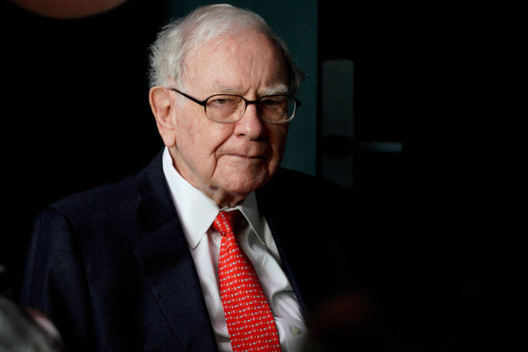 Warren Buffett, homem branco e de 93 anos, usa óculos e veste terno preto com gravata vermelha