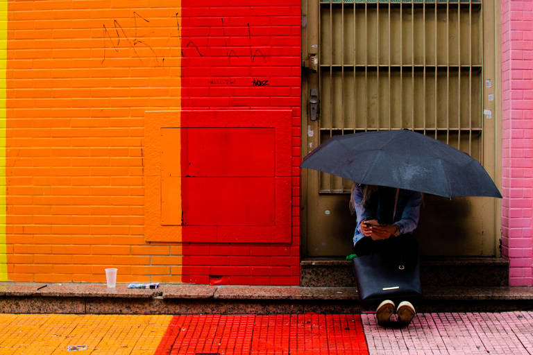 Homem de guarda-chuva em uma parede colorida 