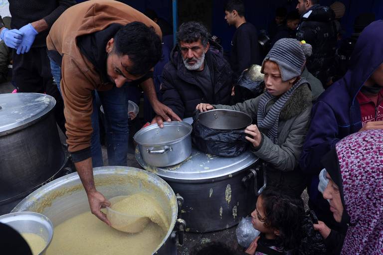 Voluntário distribui sopa para palestinos deslocados internos na região de Rafah