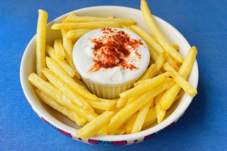 Prato de batatas fritas com um pote de maionese de leite com alho 