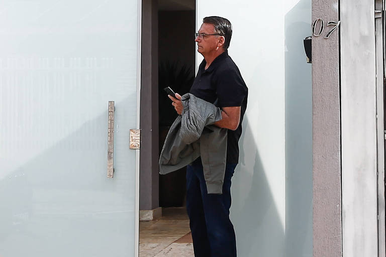 O ex-presidente Jair Bolsonaro, de pé, ao deixar sua casa no dia de seu depoimento à PF sobre a tentativa de golpe de Estado