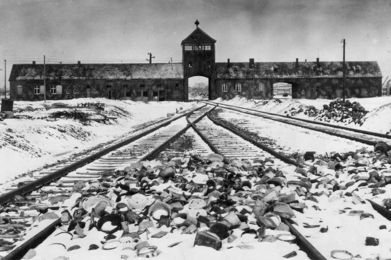 Panelas jogadas em frente ao portão por onde trens levavam os judeus para serem mortos no campo de Auschwitz, na Polônia