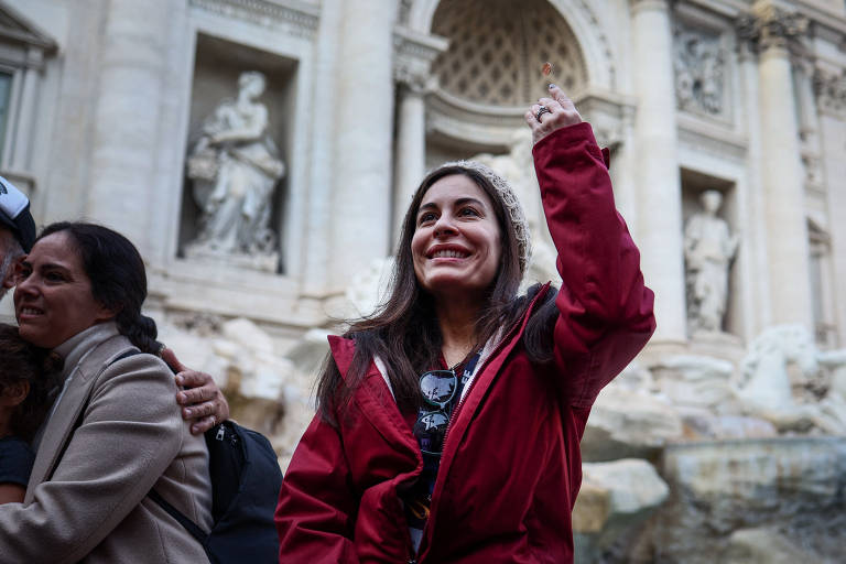 Yula Cole, do Brasil, joga uma moeda na Fontana de Trevi em Roma, Itália, em 16 de fevereiro de 2024
