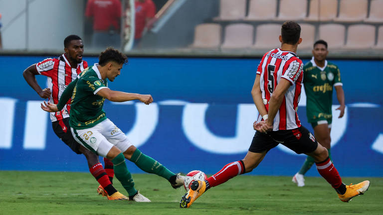 Raphael Veiga prepara finalização em partida do Palmeiras contra o Botafogo-SP; jogadores do Botafogo tentam impedir finalização