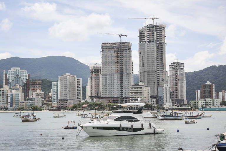 vista do mar com lanchas e ao fundo prédios em obras