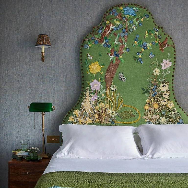 Cama com cabeceira verde e desenhos que lembram natureza