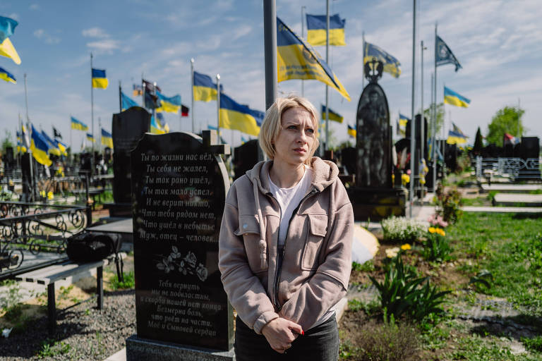 Helen Voinorovska, emocionada em frente ao túmulo de seu irmão Yurii Solomko, soldado morto em combate, em cemitério na cidade de Odessa
