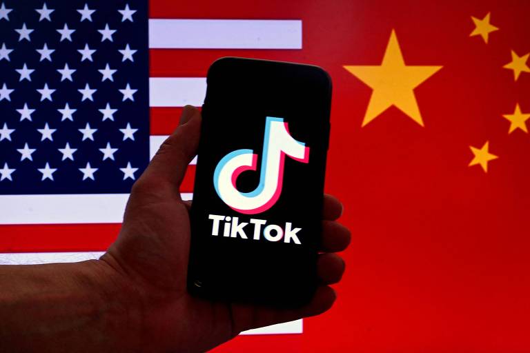 Foto ilustrativa mostra smartphone com TikTok na tela, entre bandeiras dos Estados Unidos e da China