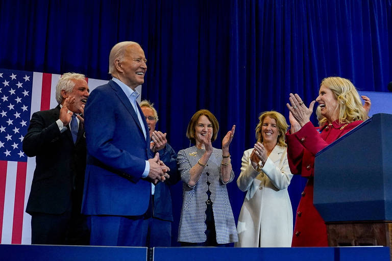 Joe Biden, um homem de 81 anos, branco e com cabelos brancos, está cercado e é aplaudido por Kathleen, Rory e Kerry Kennedy, além de outros membros da família, durante comício realizado no Centro Recreativo Martin Luther King, na Filadélfia