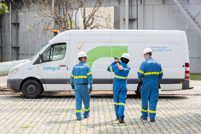 Operários carregam equipamentos em direção a uma van