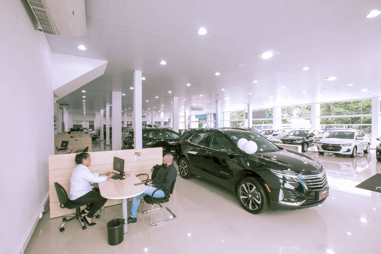 Atendente e cliente conversam em mesa de concessionária da Chevrolet