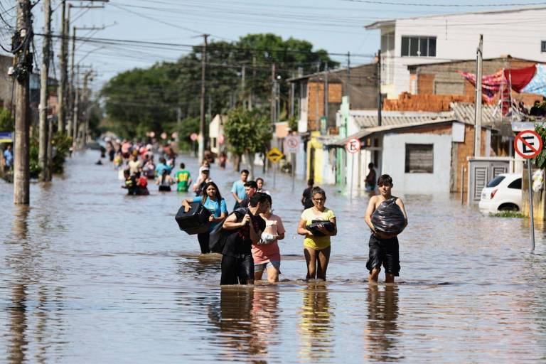 Moradores de Eldorado do Sul carregavam pertences em rua alagada
