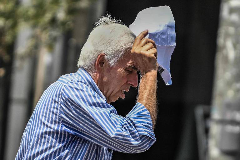 Idoso segura um papel para proteger o rosto do sol durante onda de calor em Atenas, na Grécia