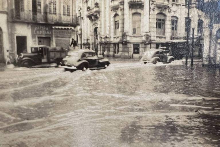 Carros passando por rua alagada