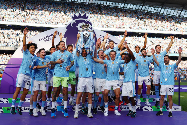 O capitão do Manchester City, Kyle Walker, ergue a taça do Campeonato Inglês no estádio Etihad, cercado pelos colegas de time; ao fundo, nas arquibancadas, a torcida