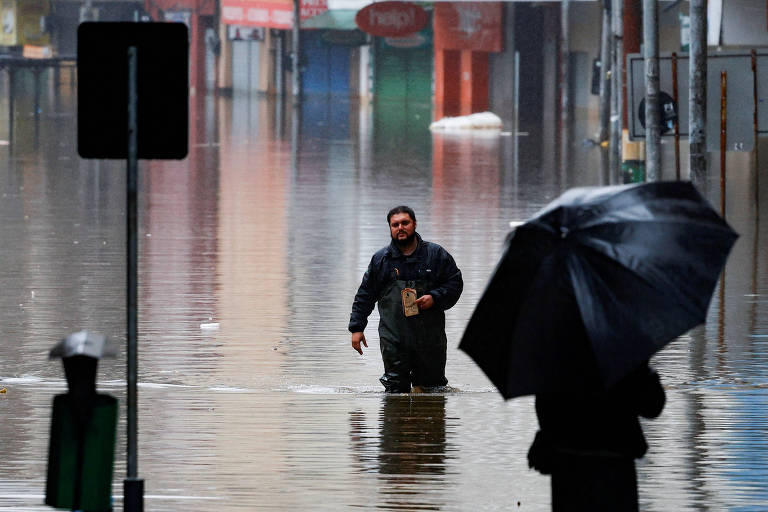 Pessoas caminham pelo centro de Porto Alegre com águas pelo joelho