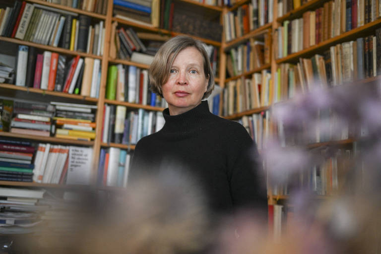 mulher loira de roupa preta em sala cheia de estantes de livros