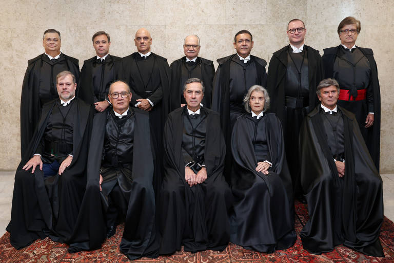 Ministros posam para foto oficial com toga; alguns estão de pé, outros sentados