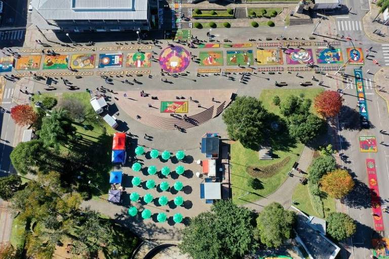 .Na foto, uma visão aérea de uma praça mostra tapetes coloridos de serragem