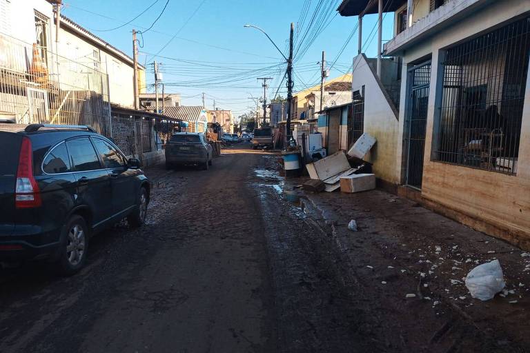 Moradores e comerciantes do bairro Farrapos, na zona norte de Porto Alegre, limpam imóveis neste sábado (1º), após enchente. Na foto, bandeira do Grêmio suja de barro.