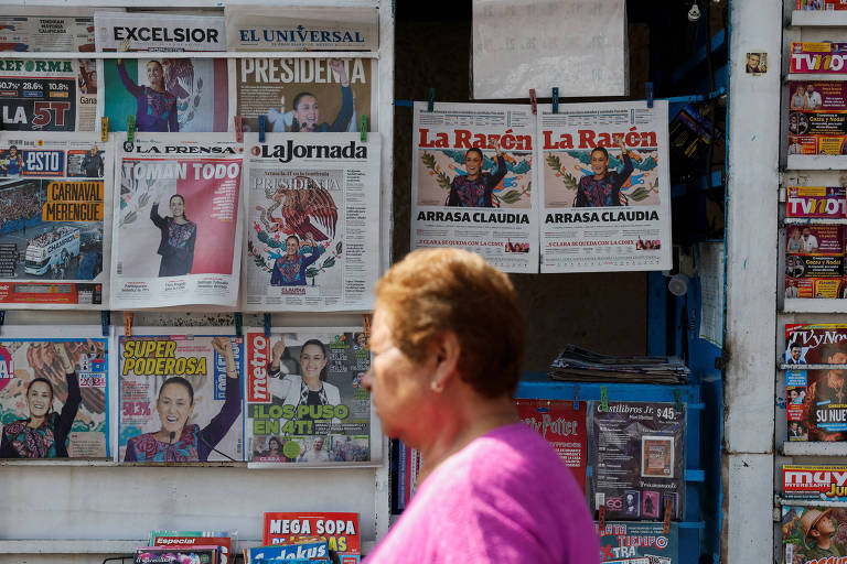 Mulher caminha perto de jornais que informam em suas capas a vitória de Claudia Sheinbaum, na capital Cidade do México