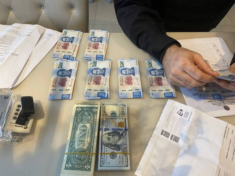Mesa com documentos e cédulas de dólar e pesos mexicanos em pequenas pilhas